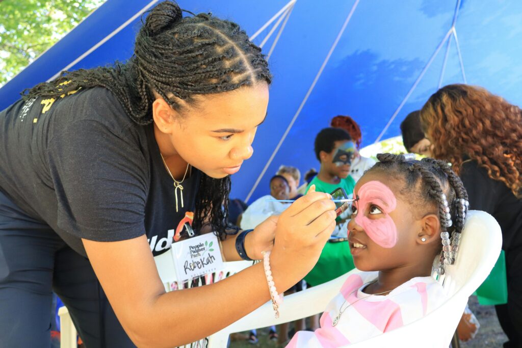 Facepainter painting young childs face.