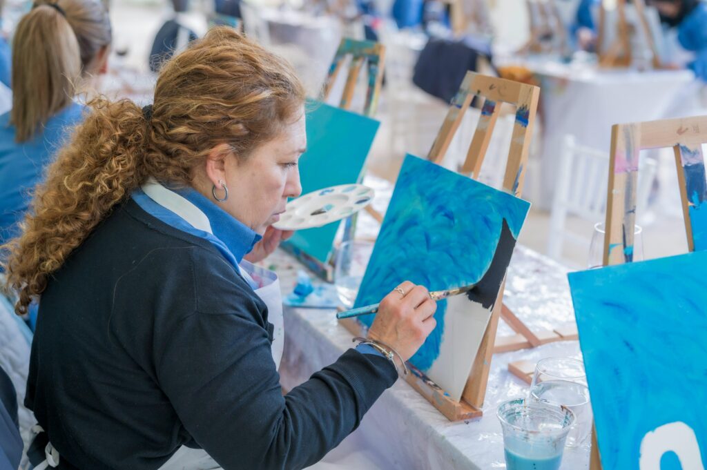 A lady painting on canvas at a sip and paint event.